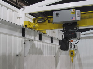 Close up image of motorized 5-ton crane which operates along a yellow beam