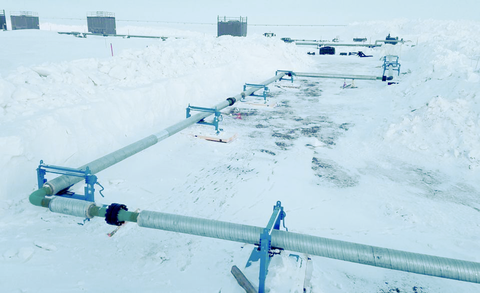 Steel Fabricated Value Stream Mapping system, insulated pipes at right angles, supported by blue brackets, outdoors in the winter